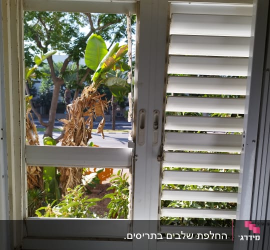 תריסים לבנים פתוחים למחצה עם ידיות מתכת